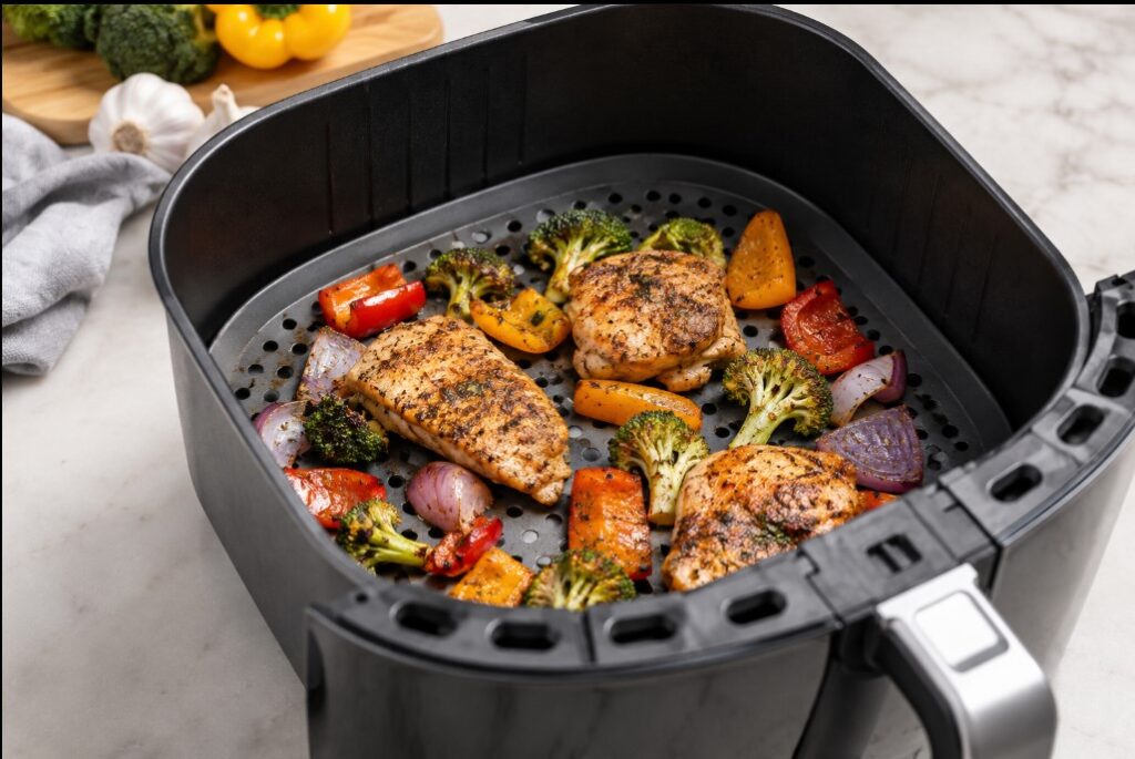 Air fryer basket with perforated liner and seasoned chicken and vegetables
