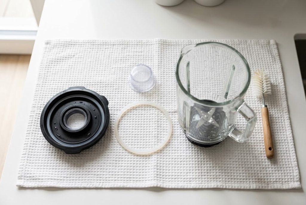 Blender lid, gasket, jar and removable components separated for cleaning.